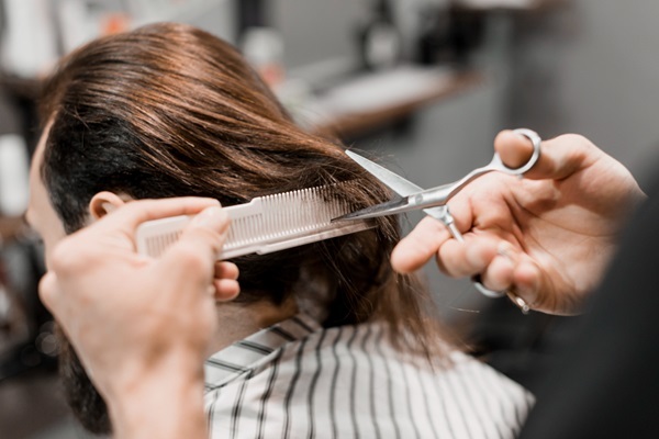 Cortar el cabello - Barbero usando tijeras para cortar el pelo largo de un hombre y eliminar las puntas abiertas haciendo cortes en tendencia