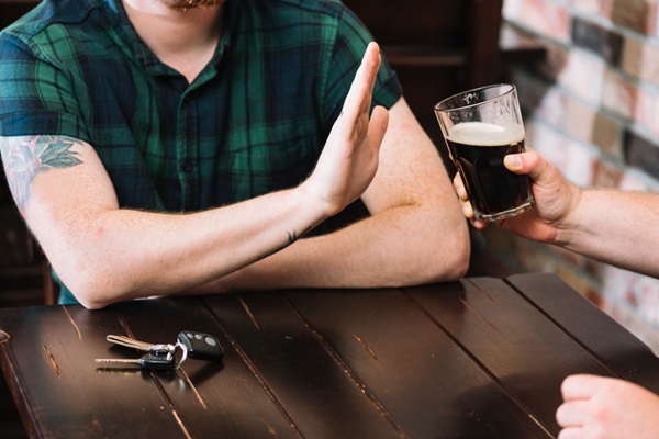 Dejar el alcohol en el injerto capilar - Hombre en un bar haciendo seña de abstinencia de tomar alcohol por el trasplante cabello