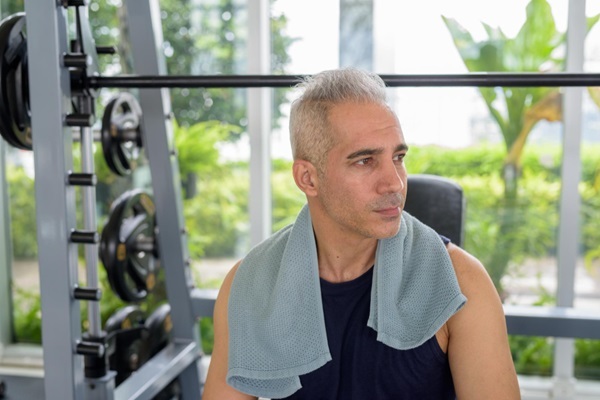 Gimnasio tras injerto capilar - Hombre entrenando con pesas en un gimnasio después de la cirugía de trasplante capilar