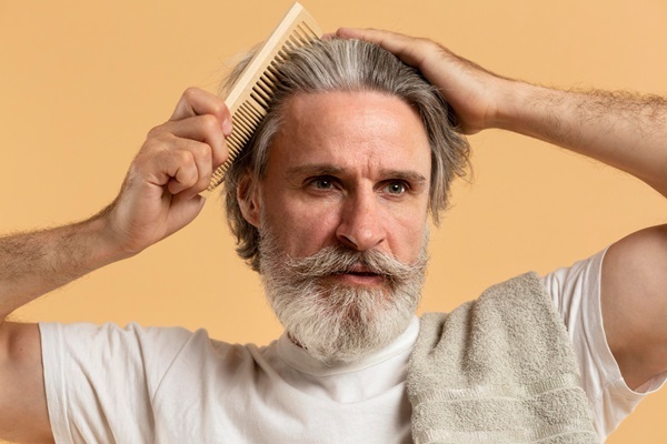 Injerto de pelo con canas - Hombre peinando su cabello con canas abundante y natural luego de un implante capilar