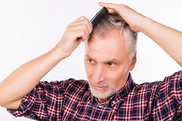 Injerto de pelo con canas - Hombre con caída del cabello en las entradas peinando su pelo canoso por falta de melanina