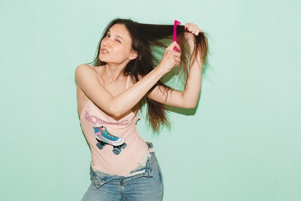 Peinar cada tipo de pelo - Mujer con cara de sufrimiento al no saber cómo peinar el cabello lacio para crear mayor volumen capilar