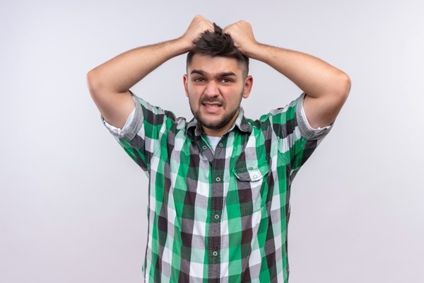 Picores por Minoxidil - Hombre joven halando su cabello con desesperación sin saber qué hacer con los picores por minoxidil