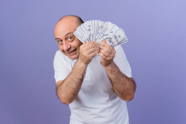 Injerto capilar precio - Hombre con problemas de alopecia sosteniendo billetes buscando saber el injerto cabello costo CDMX
