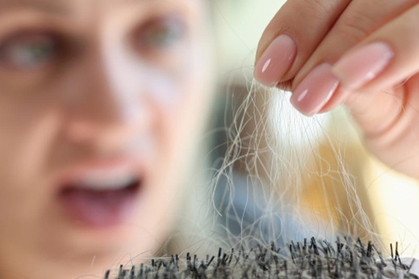 Caída del pelo con raíz blanca - Mujer con cara de asombro observando todo el pelo con raíz blanca que cae al peinarse