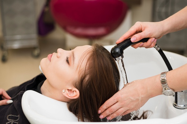Formaldehído para alisar el pelo - Peluquera lavando el cabello de una mujer para eliminar residuos de tratamientos de queratina para alisar el pelo