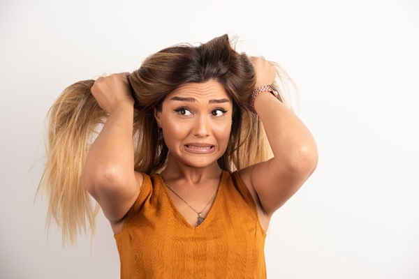 Problemas capilares distintos a la alopecia - Mujer jalándose los pelos con cara de desesperación debido a afecciones capilares que causan picazón en el cabello