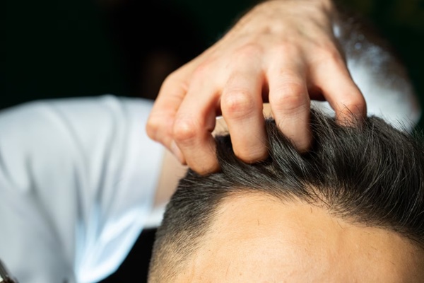 Añadir volumen al cabello fino - Estilista peinando el cabello fino de un hombre usando productos capilares para añadir volumen al cabello fino