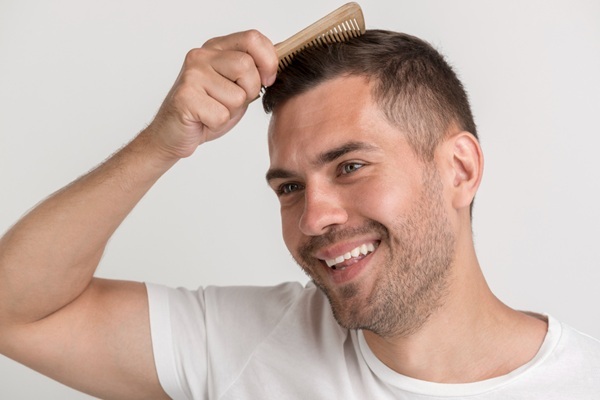 Hombre feliz peinando su pelo abundante y natural luego de un trasplante capilar CDMX