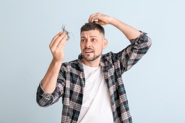 Jengibre para fortalecer el cabello - Hombre preocupado por la caída del pelo debido a una rutina de cuidado capilar inadecuada