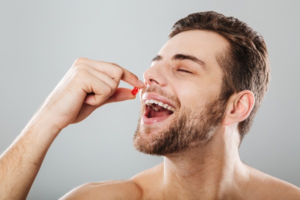Lambdapil - Hombre tomando una cápsula anticaída del cabello para frenar el avance de la alopecia como parte del tratamiento capilar efectivo
