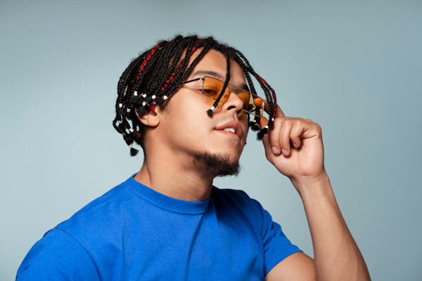 Peinados de verano - Hombre con peinado de trenzas que ayuda a mantener la hidratación del pelo y evitar la caída del cabello en verano