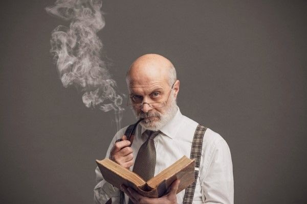Tabaco y alopecia - Hombre con pérdida capilar fumando tabaco mientras lee un libro