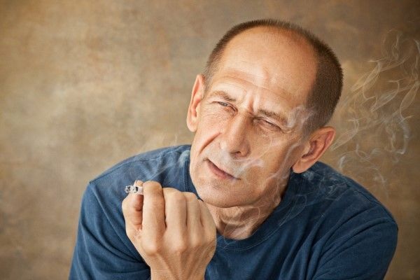 Tabaco y alopecia - Hombre pensativo fumando tabaco que acelera la caída del cabello y ocasiona alopecia prematura