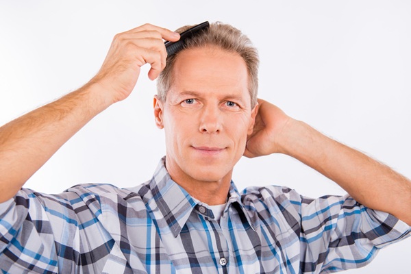 Implante de cabello - Hombre feliz peinando su cabello abundante y natural luego de un injerto cabello CDMX que ayuda a recuperar la autoestima
