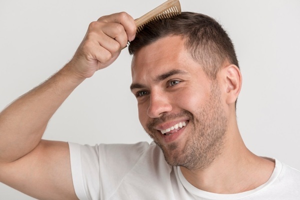 Hombre feliz peinando su pelo natural luego de un tratamiento de trasplante capilar CDMX