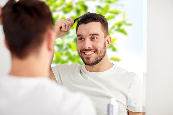 Hombre feliz peinando su pelo abundante luego de un injerto cabello CDMX