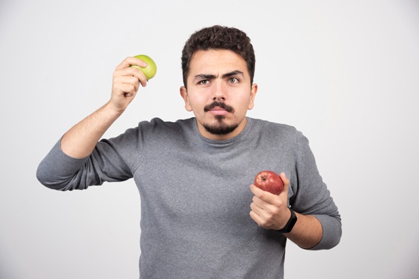 Por qué no me crece el cabello - Hombre sosteniendo unas manzanas que aporta nutrientes esenciales para saber cómo crecer el cabello